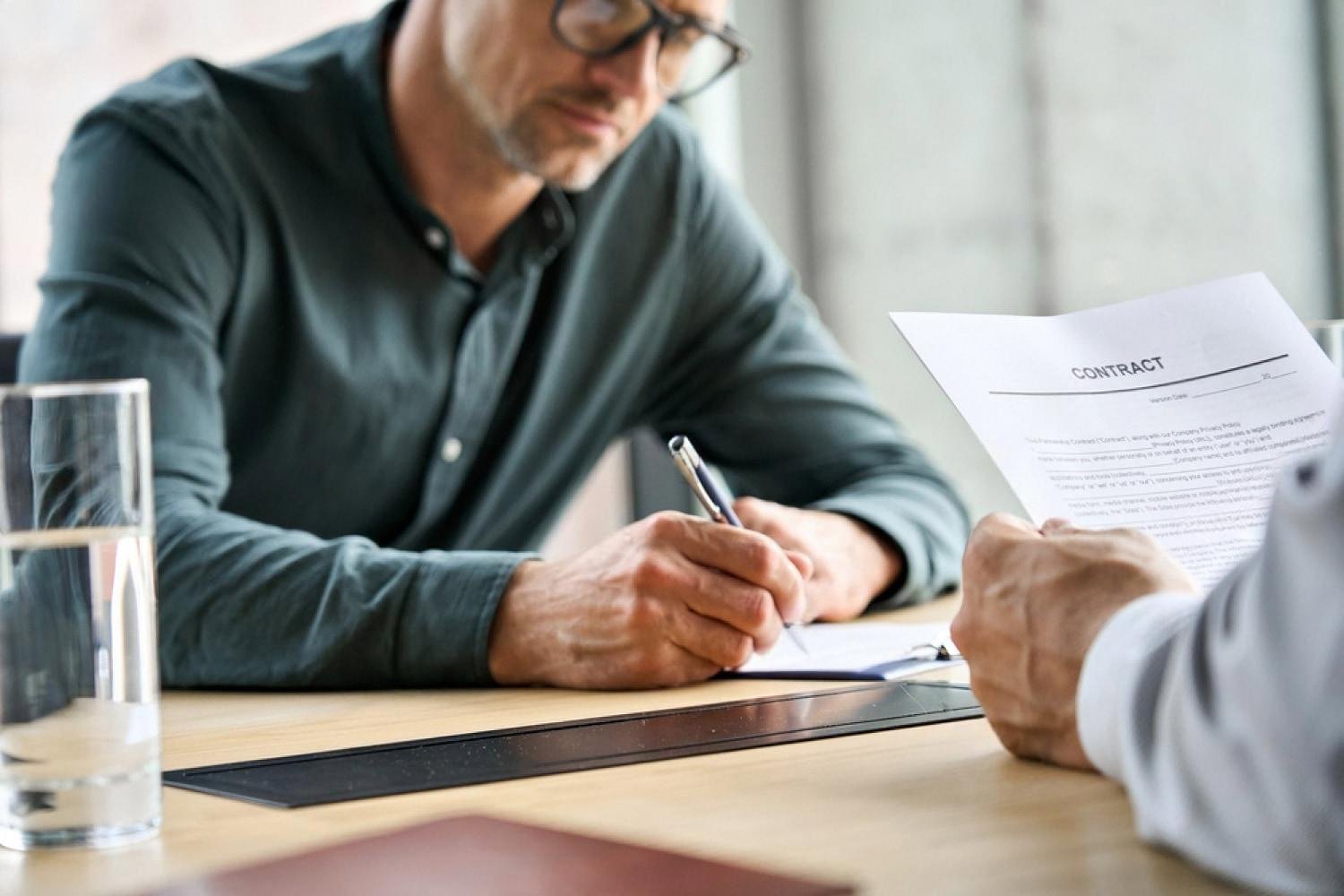 Client signing an insurance policy contract with a broker in a Dubai office