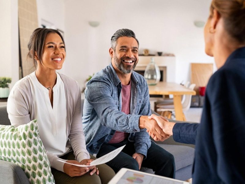 Couple shaking hands with a reliable insurance broker in Dubai after signing a policy