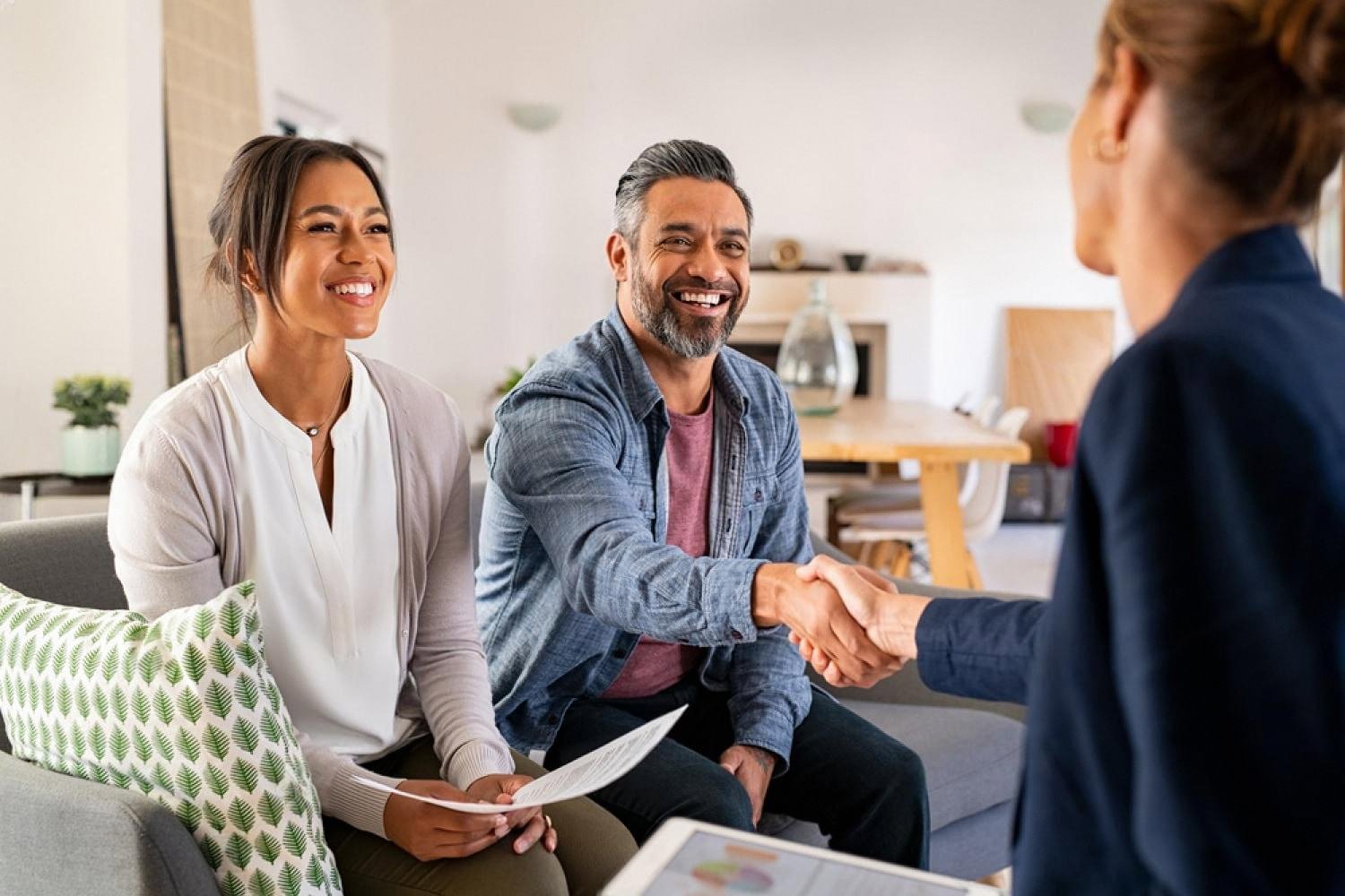 Couple shaking hands with a reliable insurance broker in Dubai after signing a policy